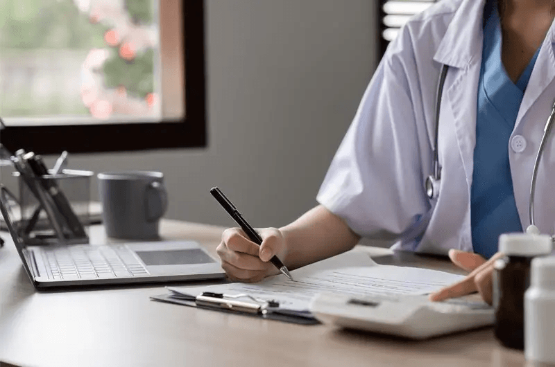 Doctor working on laptop reviewing billing files
